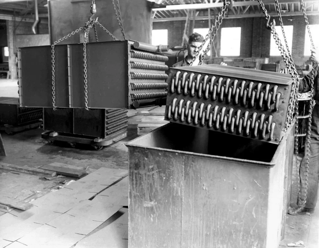 Black and White Photo of workers dipping coil