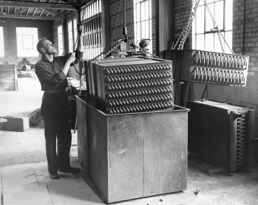 Black and White Photo of workers dipping coils